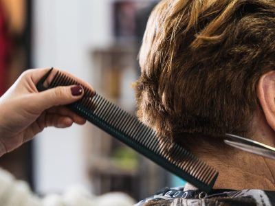 A vertical closeup shot of a hairdresser cutting a woman's short hair in a beauty salon